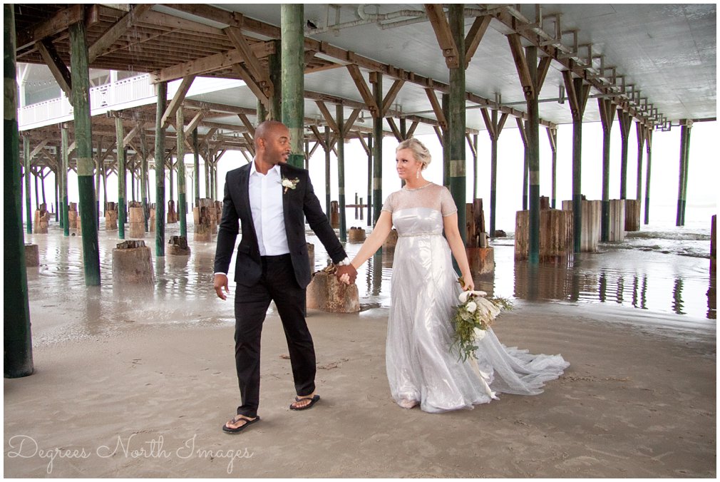 Bride and groom walking under pier on Galveston Island