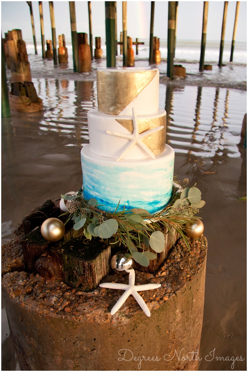 Aqua, gold and white 3-tier round wedding cake with starfish and ornaments