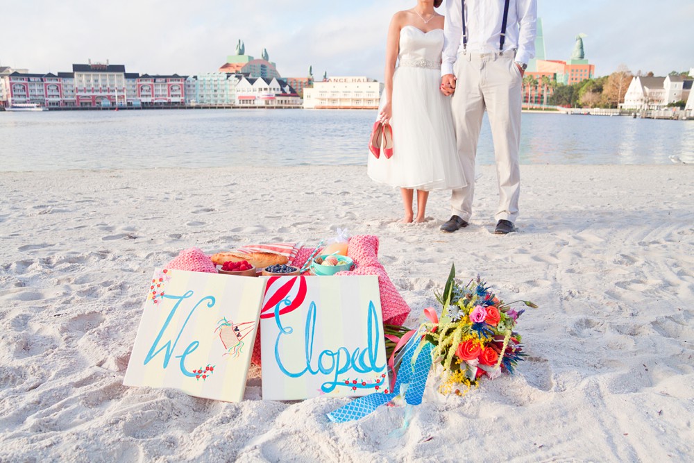 Bride and groom on beach at Disney's Beach Club Resort with just eloped signs