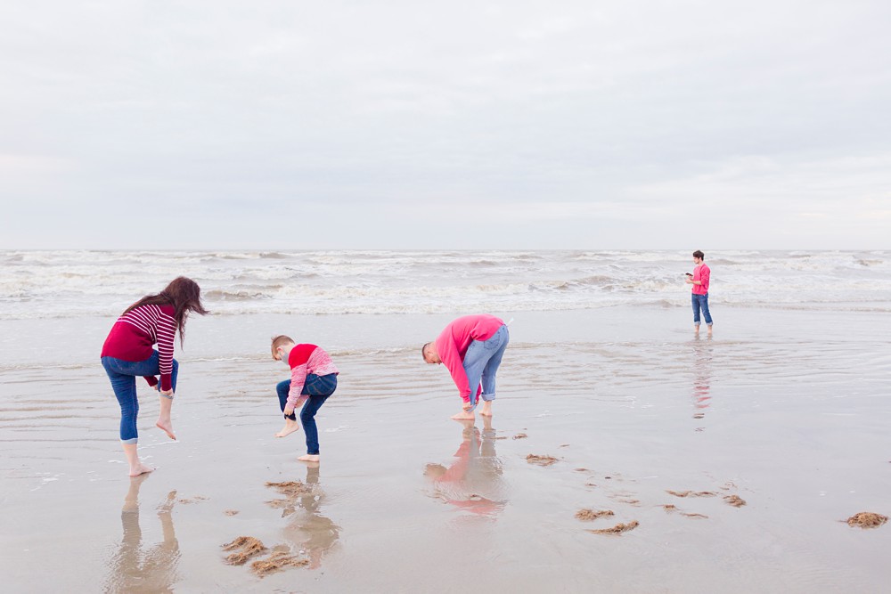 family wading into the ocean in Galveston