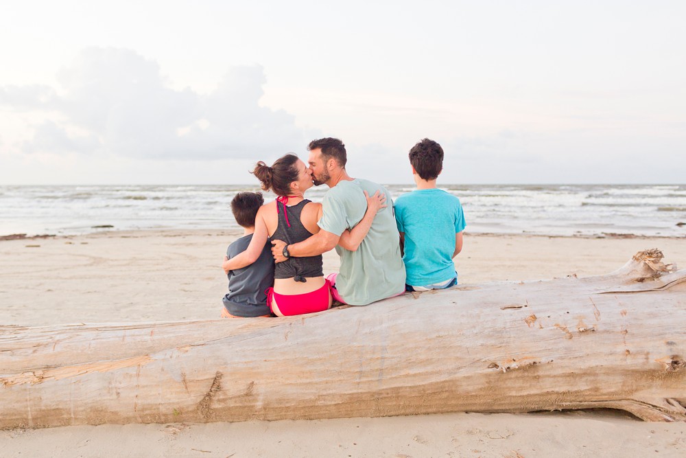 Family sitting on a large piece of driftwood during sunrise in Galveston