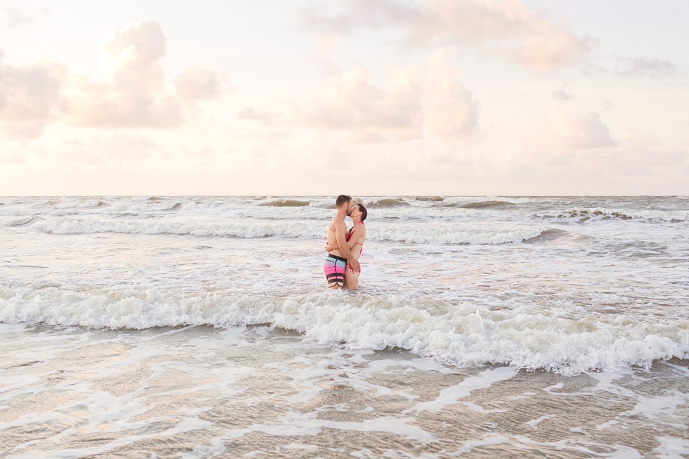 husband and wife kissing in the water at Galveston beach family session