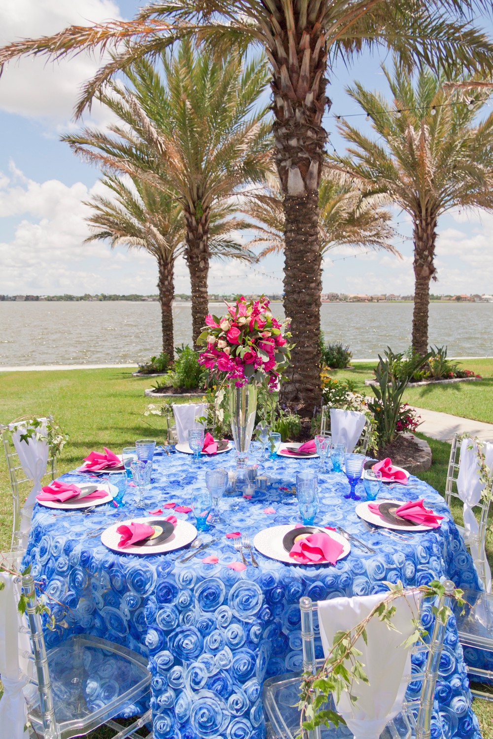 Tall wedding centerpiece with hot pink roses on a cobalt blue table cloth