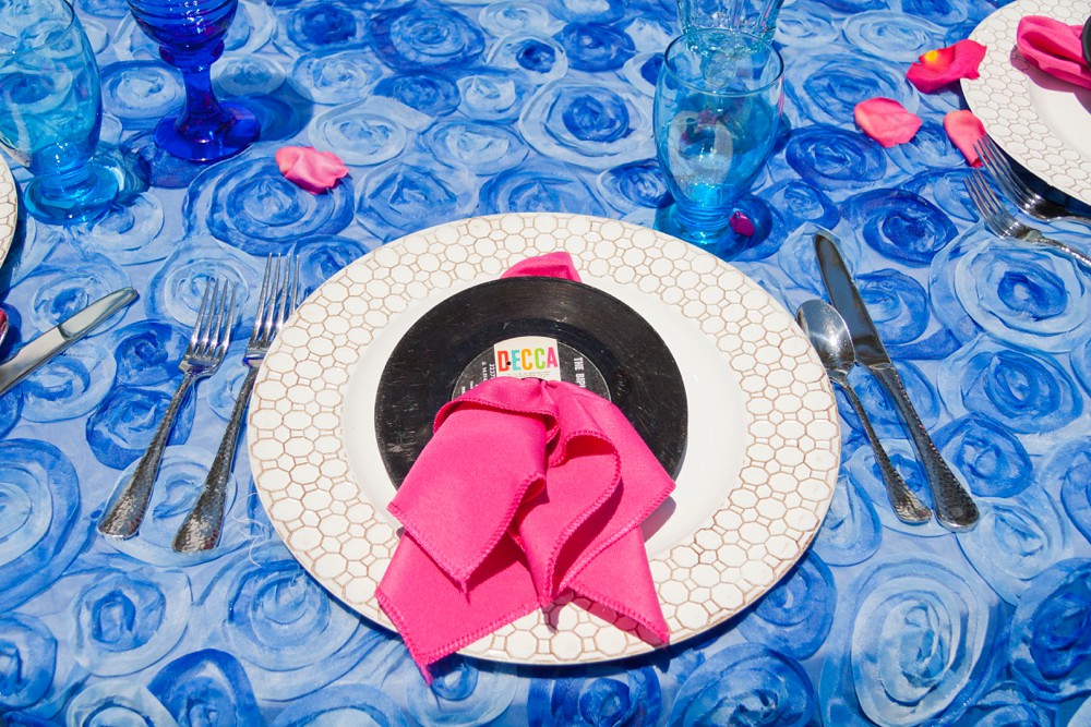 Mamma Mia wedding reception place setting with blue tablecloth and mini vinyl records as napkin holders