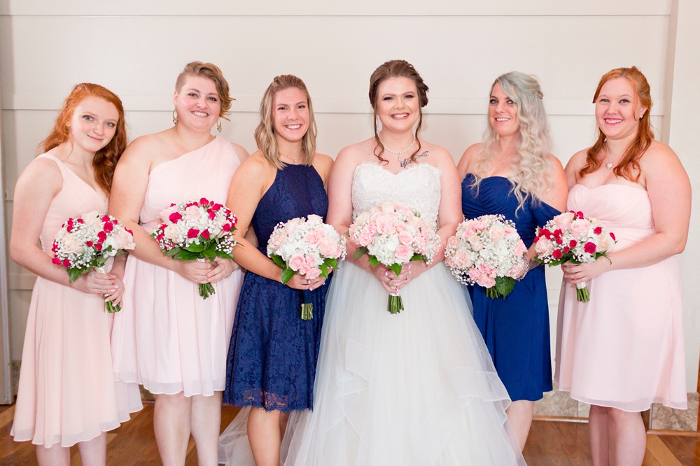 Bride with maids of honor in navy blue and bridesmaids in pale pink