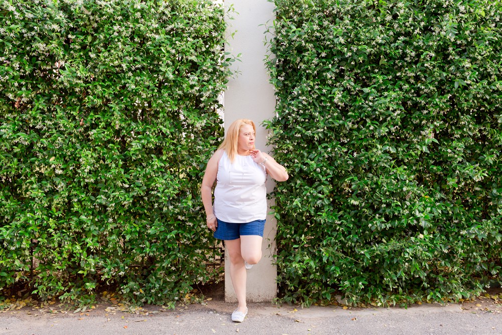 woman standing against a wall of jasmine vines