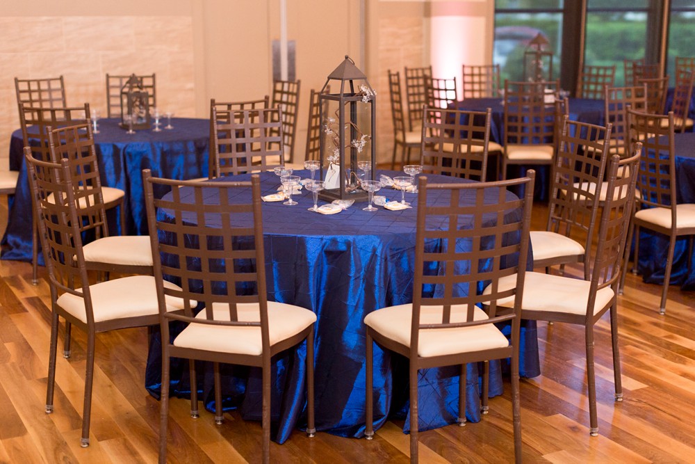 Reception table at modern wedding at Noah's Event Venue with navy blue linen, iron lantern centerpiece, iron lattice chairs