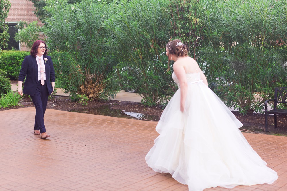 Excited bride and bride sharing a first look outside at modern wedding at Noah's Event Venue in Sugar land Texas