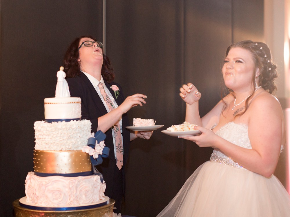 Bride and bride laughing after smashing wedding cake on each other