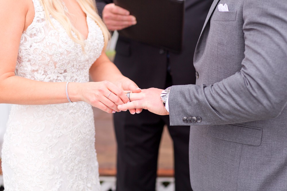 bride putting ring on groom's hand at wedding ceremony