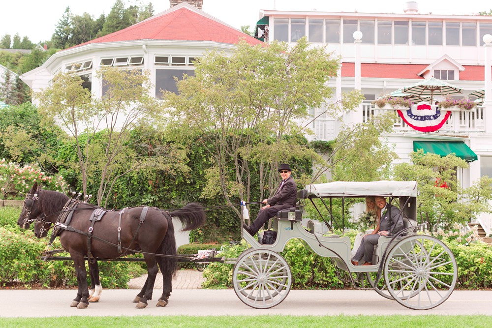 Bride and groom in horse drawn carriage in front of Mission Point Resort