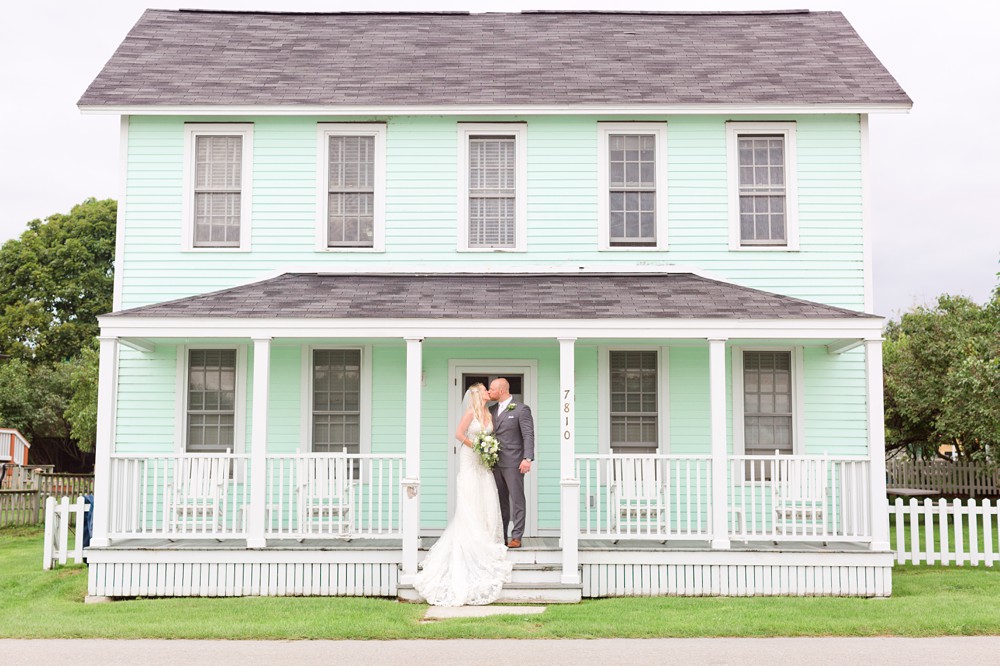 Bride and groom on the porch of a mint green house on Mackinac Island