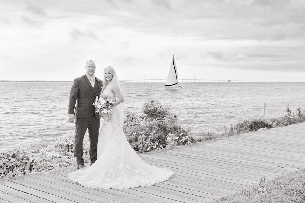 Bride and groom portrait with a sailboat and the Mackinac Bridge in the background