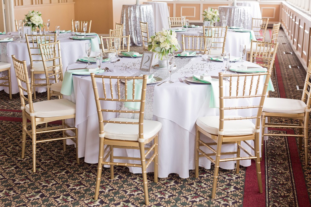 Wedding table in The Summit Room with gold chiavari chairs and silver sequin table runners