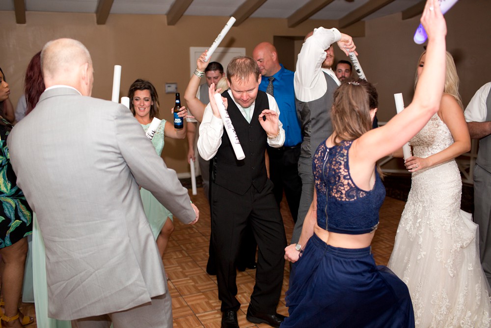 Guests dancing with personalized glow sticks at wedding reception