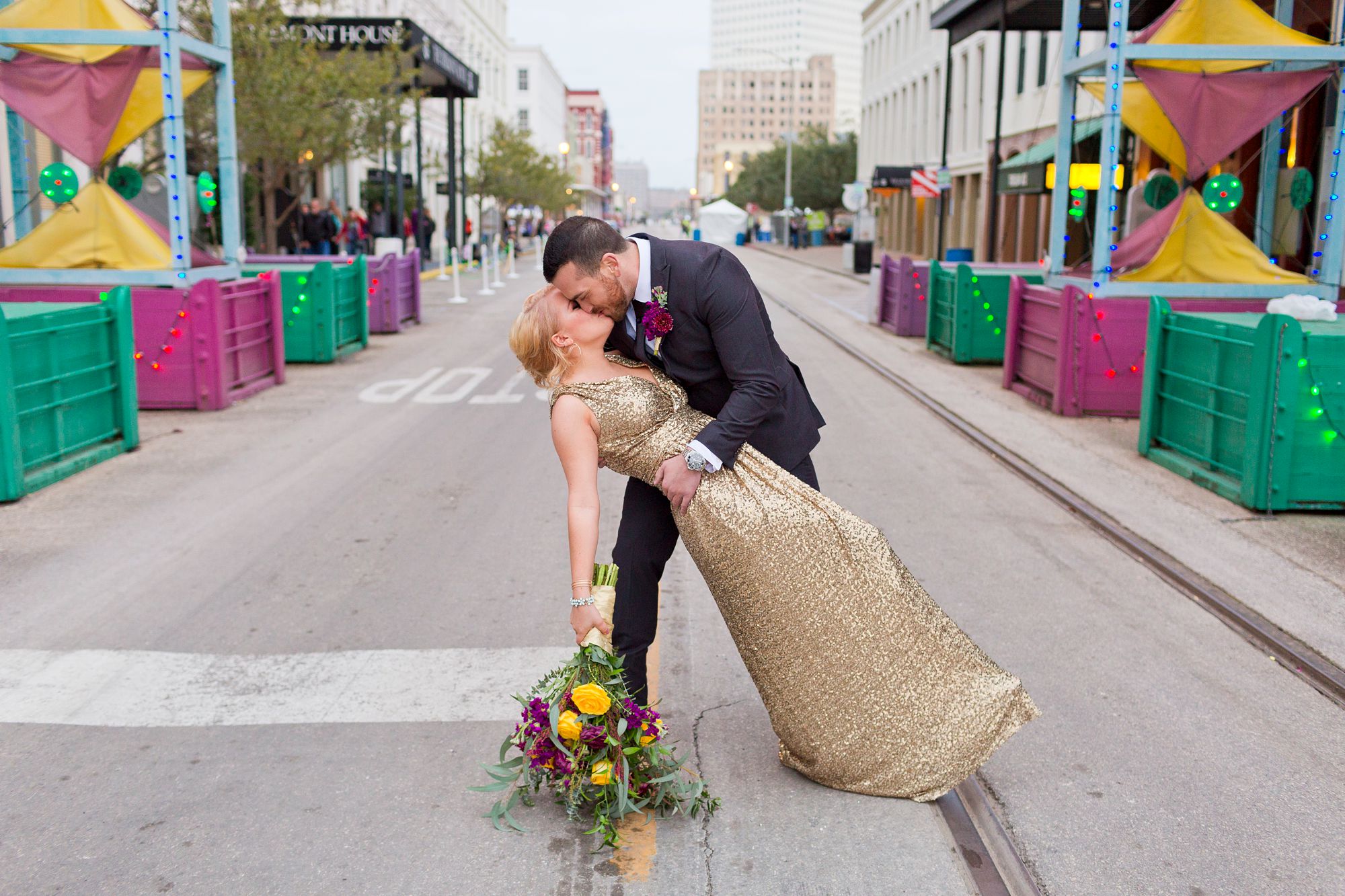 A groom dips his bride under the Powell Mardi Gras Arch in Galveston, Texas.