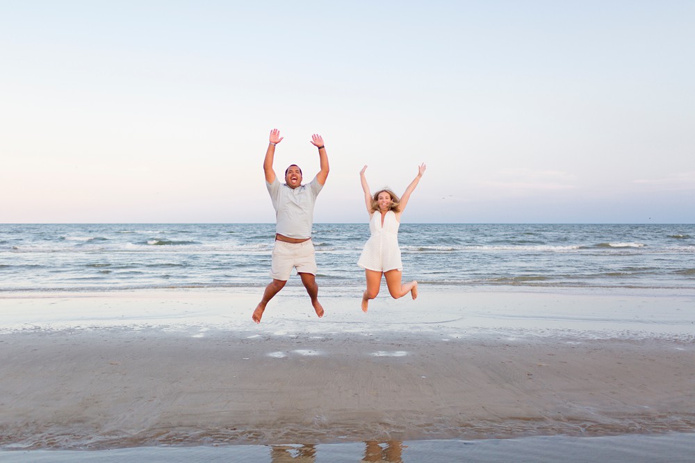 Couple jumping during engagement photos on Galveston Island beach at sunset