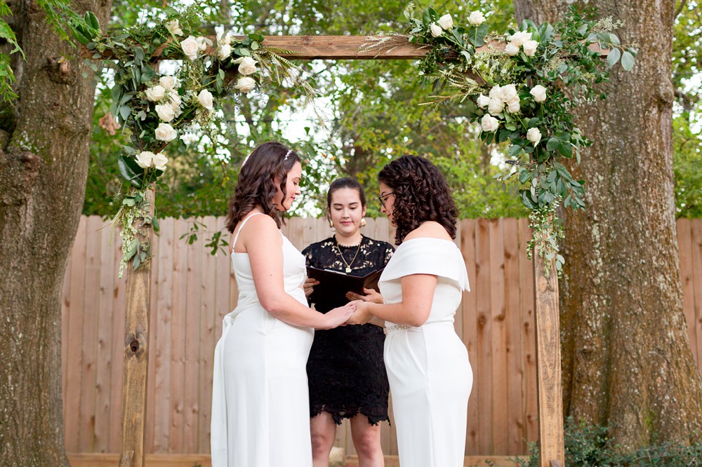 Brides exchanging rings at their backyard wedding ceremony