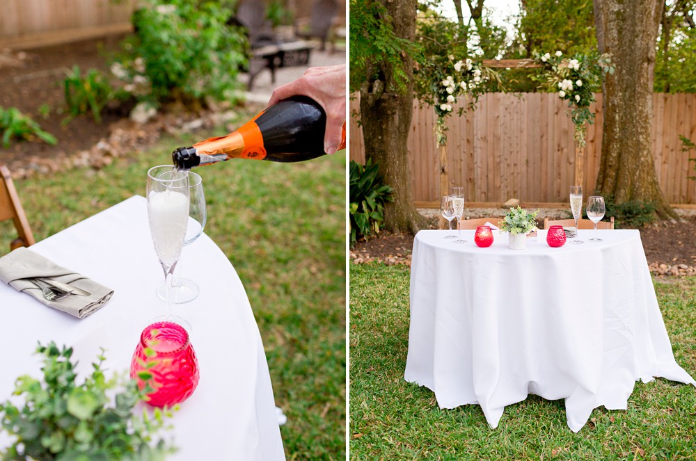 Sweetheart table at backyard wedding; guest pouring champagne for the brides
