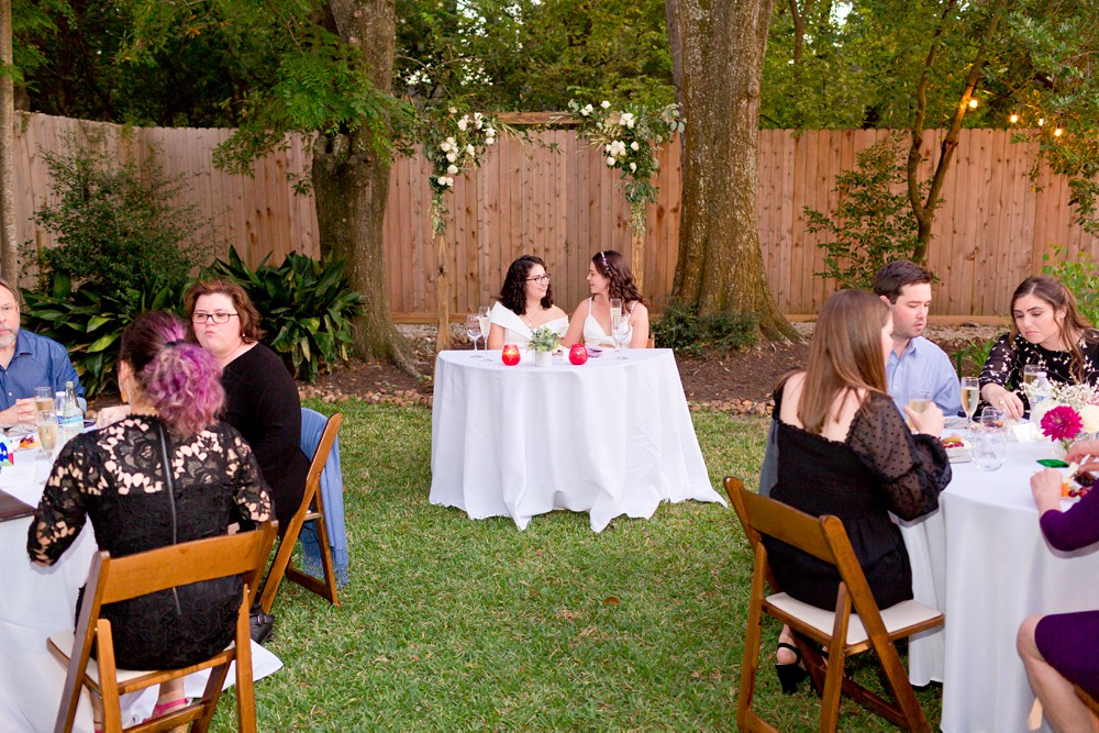 Brides sitting at sweetheart table at their backyard wedding