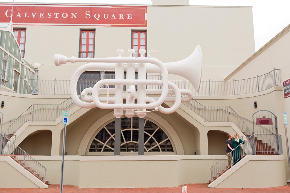 Couple posing under the cornet sculpture at Old Galveston Square