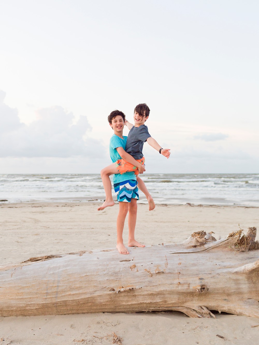 Two brothers on a large piece of driftwood in Galveston