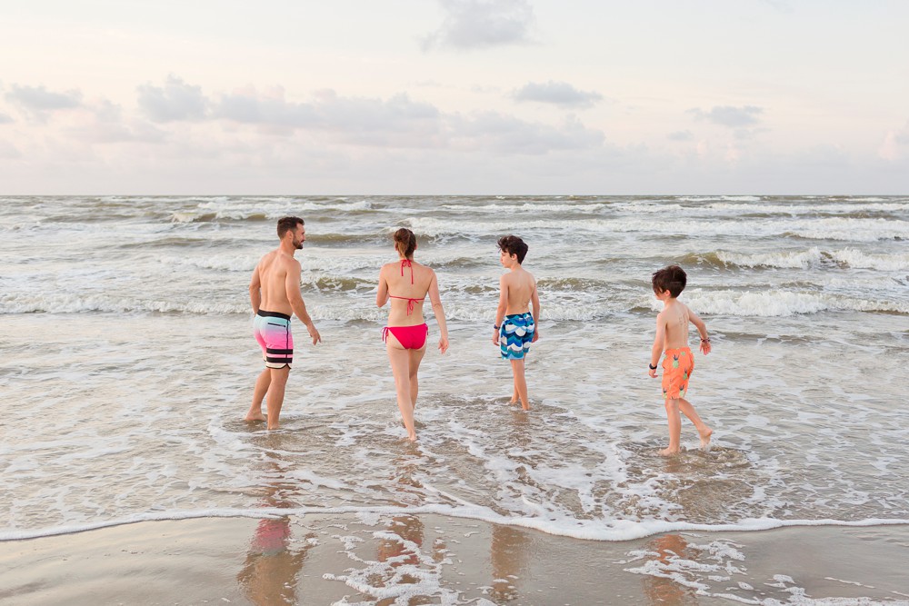 Family walking into the ocean on Galveston beach