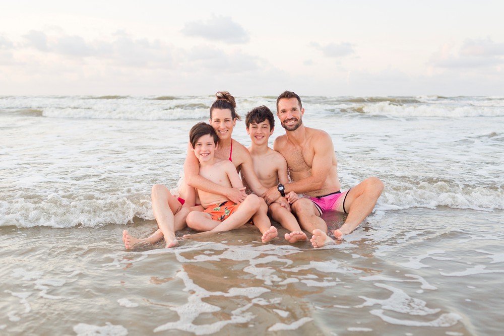 family sitting together in the ocean at Galveston beach