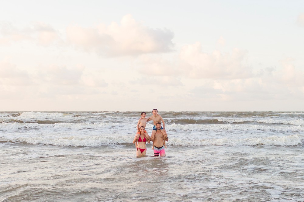 parents with kids on their shoulders in the ocean at Galveston beach