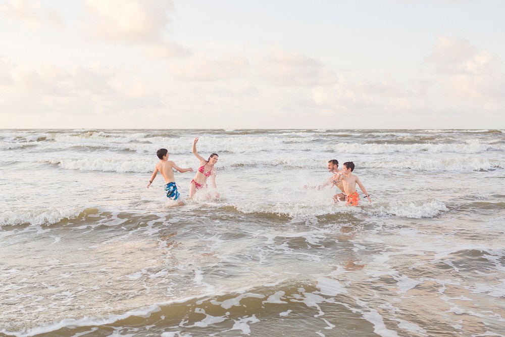 family having a water fight at their Galveston beach family session