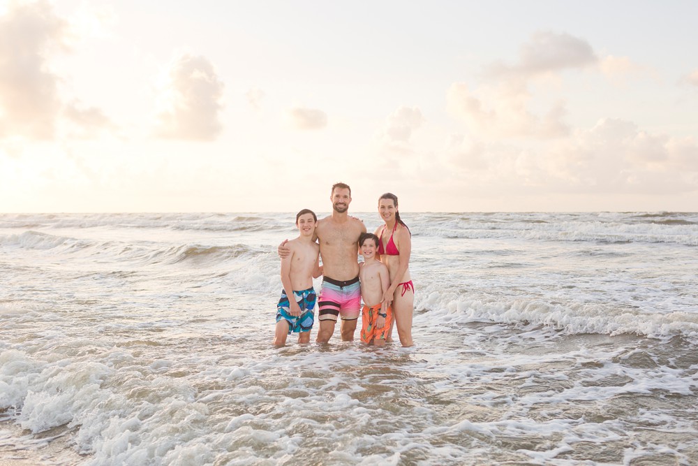 Family posing in the water at their Galveston beach family session
