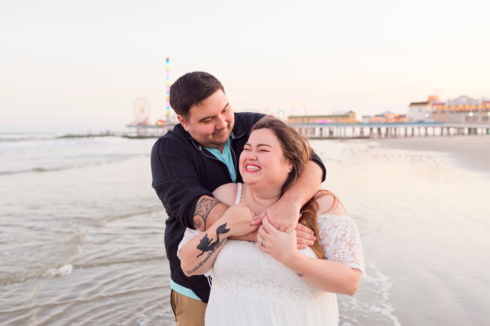 Couple laughing on Galveston Beach with Pleasure Pier in the background
