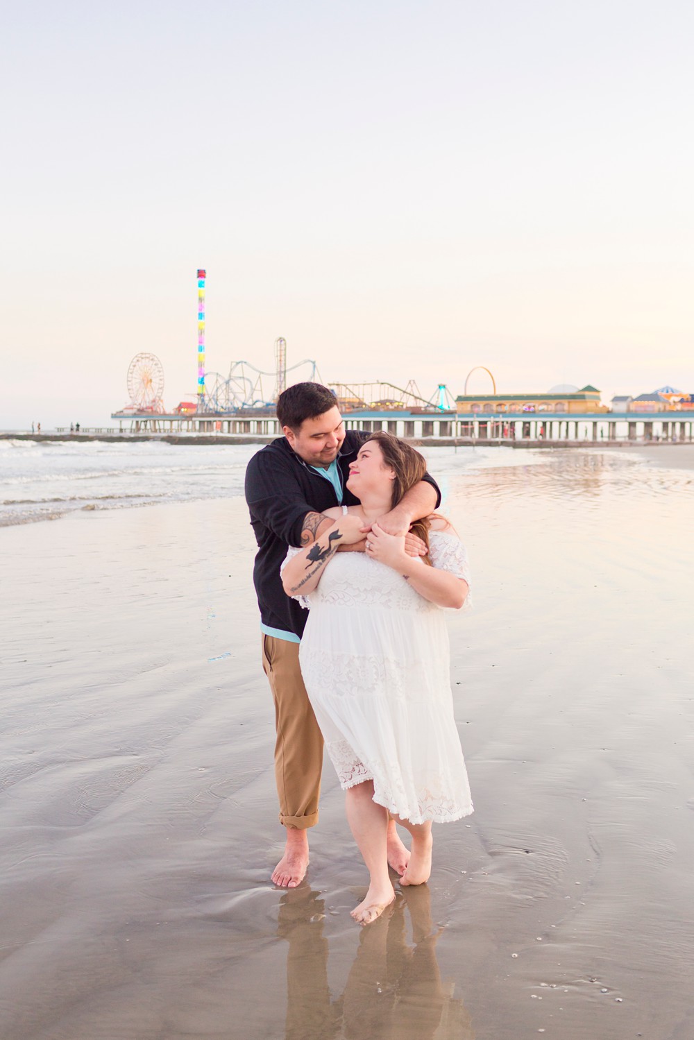 Couple on Galveston Beach at sunset with Pleasure Pier in the background