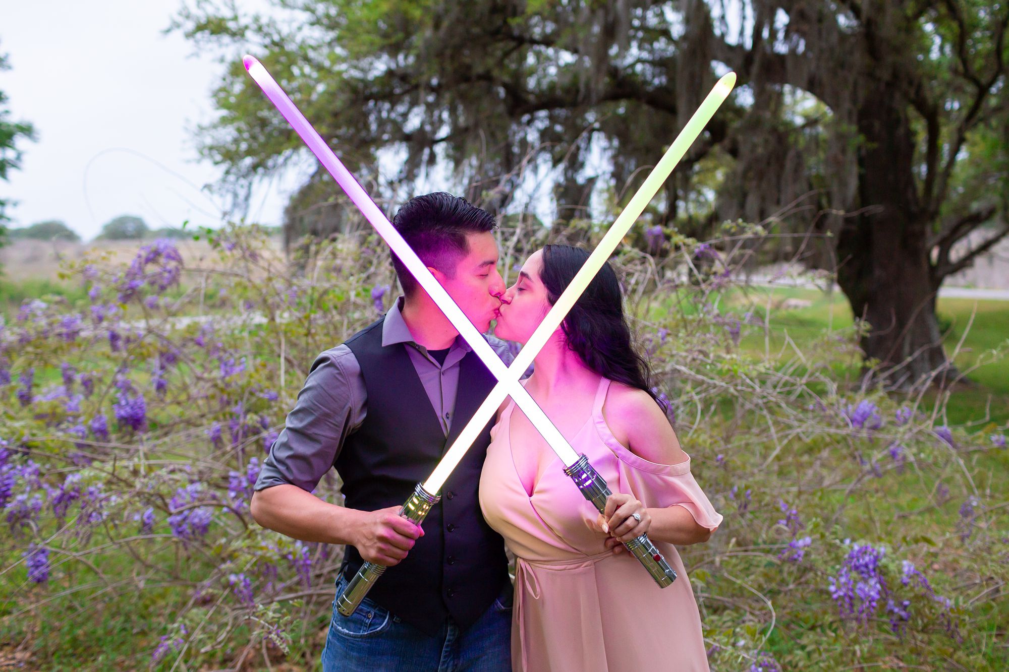 Man and woman holding lightsabers at their engagement session.
