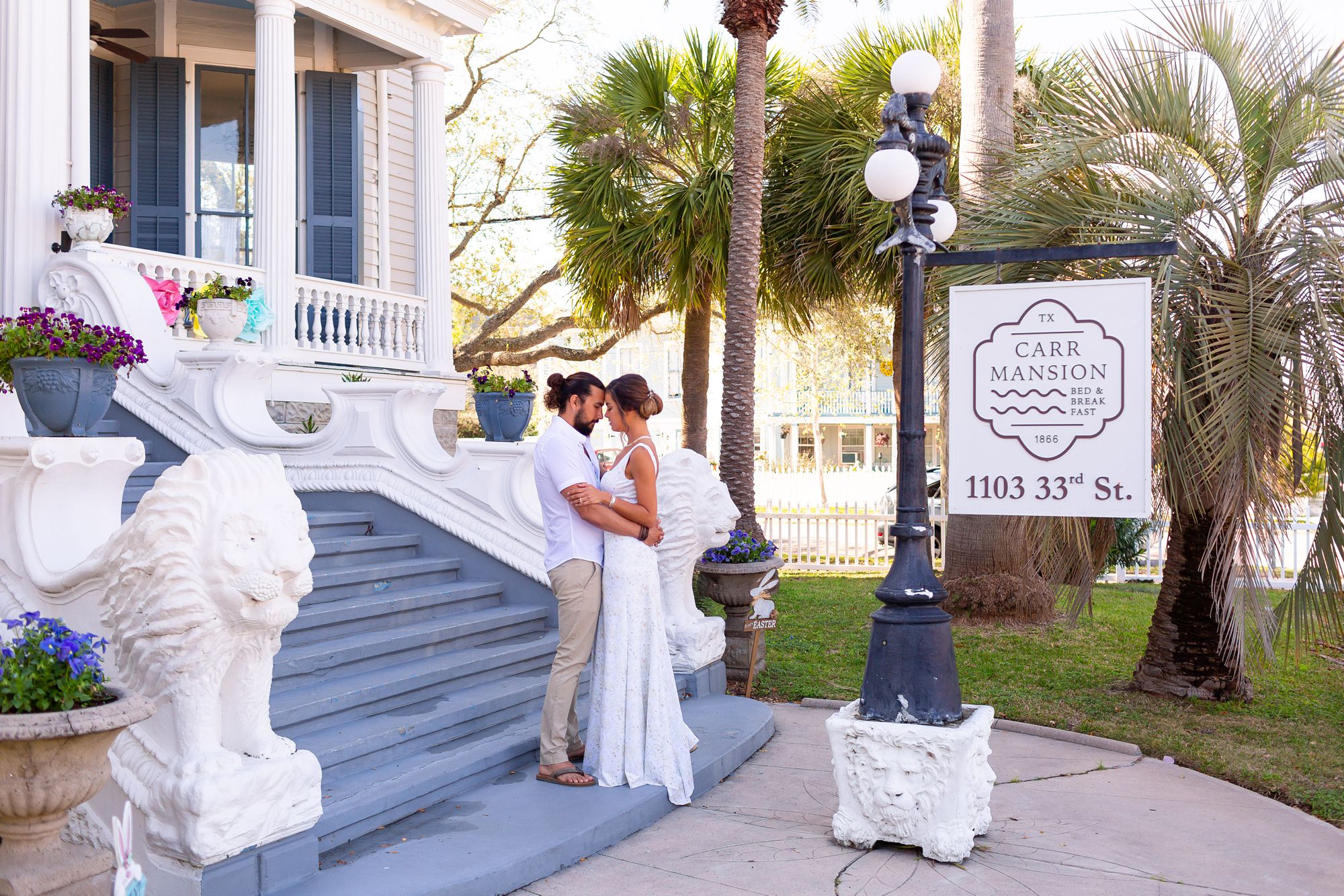 A bride and groom embrace on the front steps of the Carr Mansion.