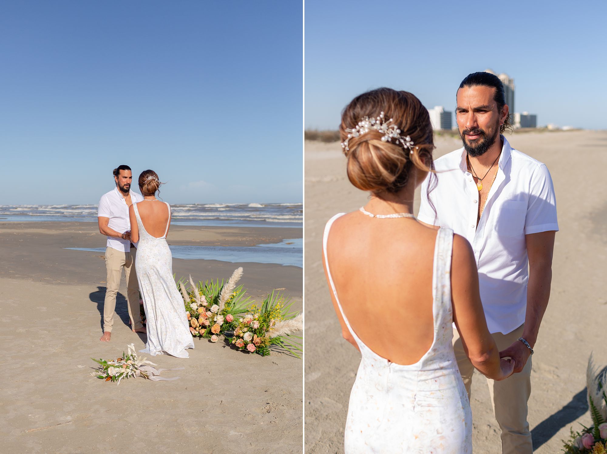 A bride and groom stand facing each other and holding hands in front of a ceremony flower arrangement on a Galveston beach.