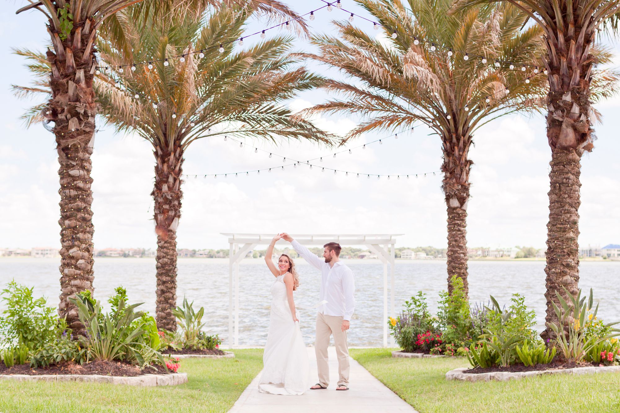 Bride and groom dance under palm trees at Waters Edge wedding venue in El Lago, Texas.
