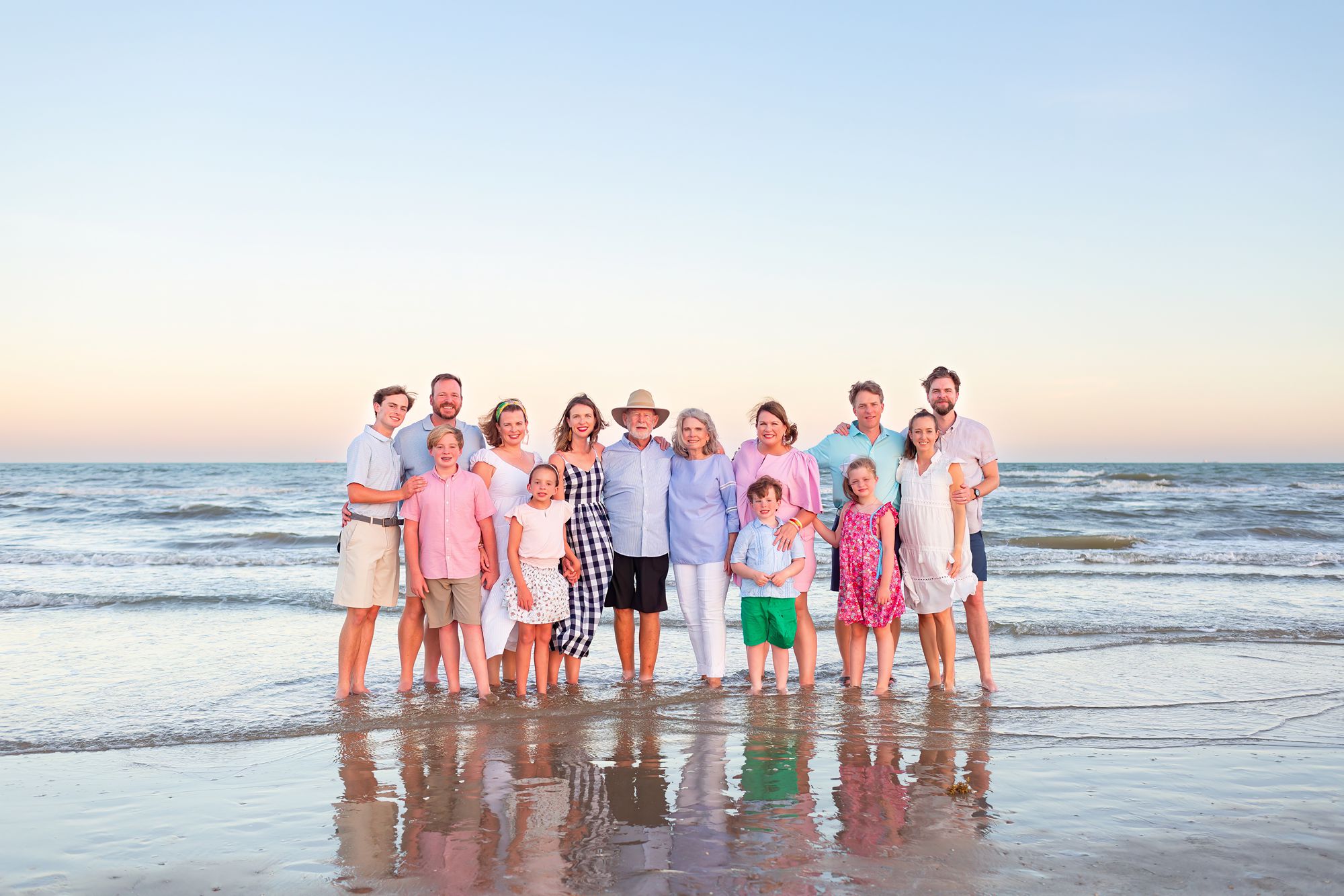 A couple stands in the water with their children and grandchildren at a Crystal Beach Extended Family session in Texas.