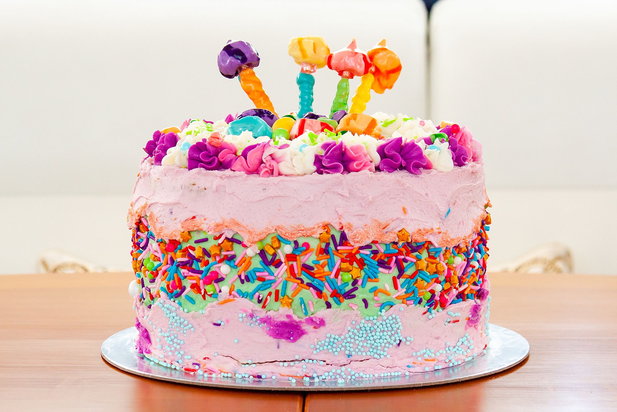 Lisa Frank inspired adult vegan birthday cake with pink, purple, and green frosting, multicolored sprinkles, and saltwater taffy from La Kings in Galveston.
