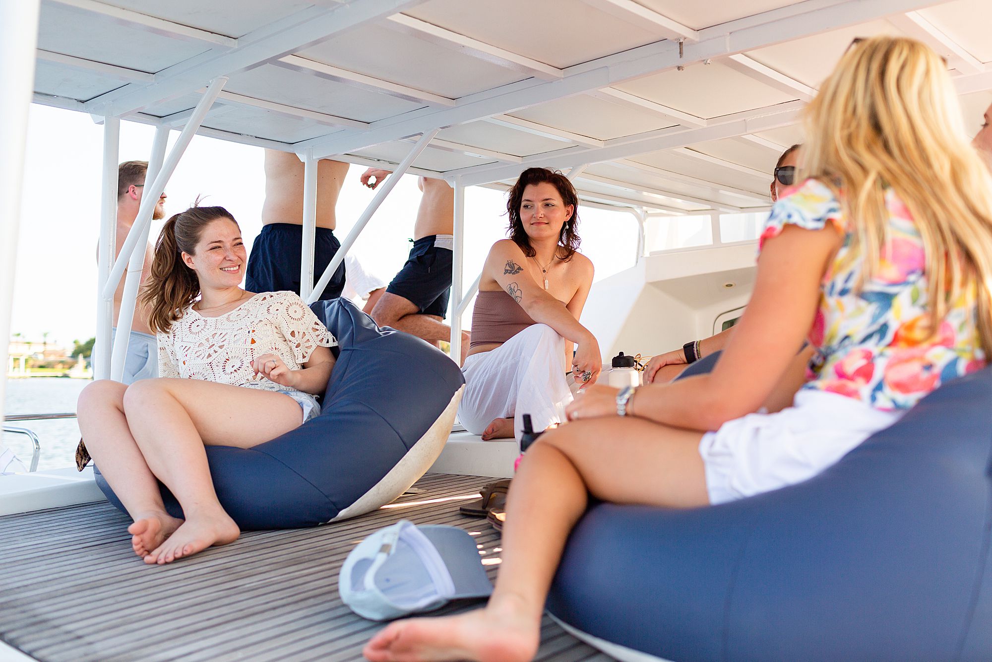 A group of women laugh together on the lower deck of a catamaran.