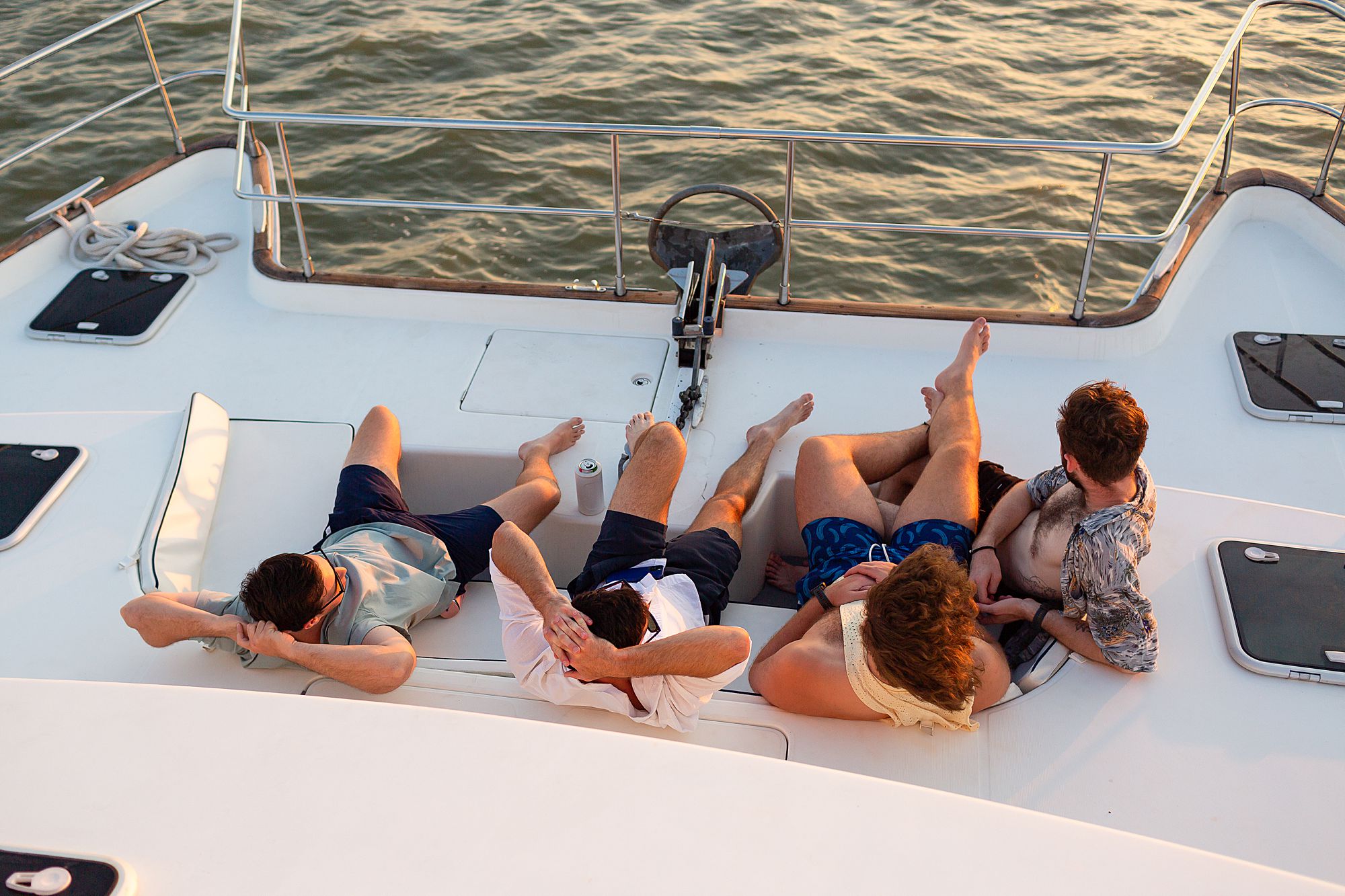 A group of men sit back on the lower deck of a catamaran to enjoy sunset over Galveston.