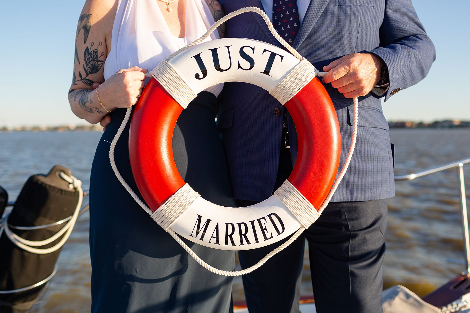 A bride and groom holding a red and white life ring that says just married.