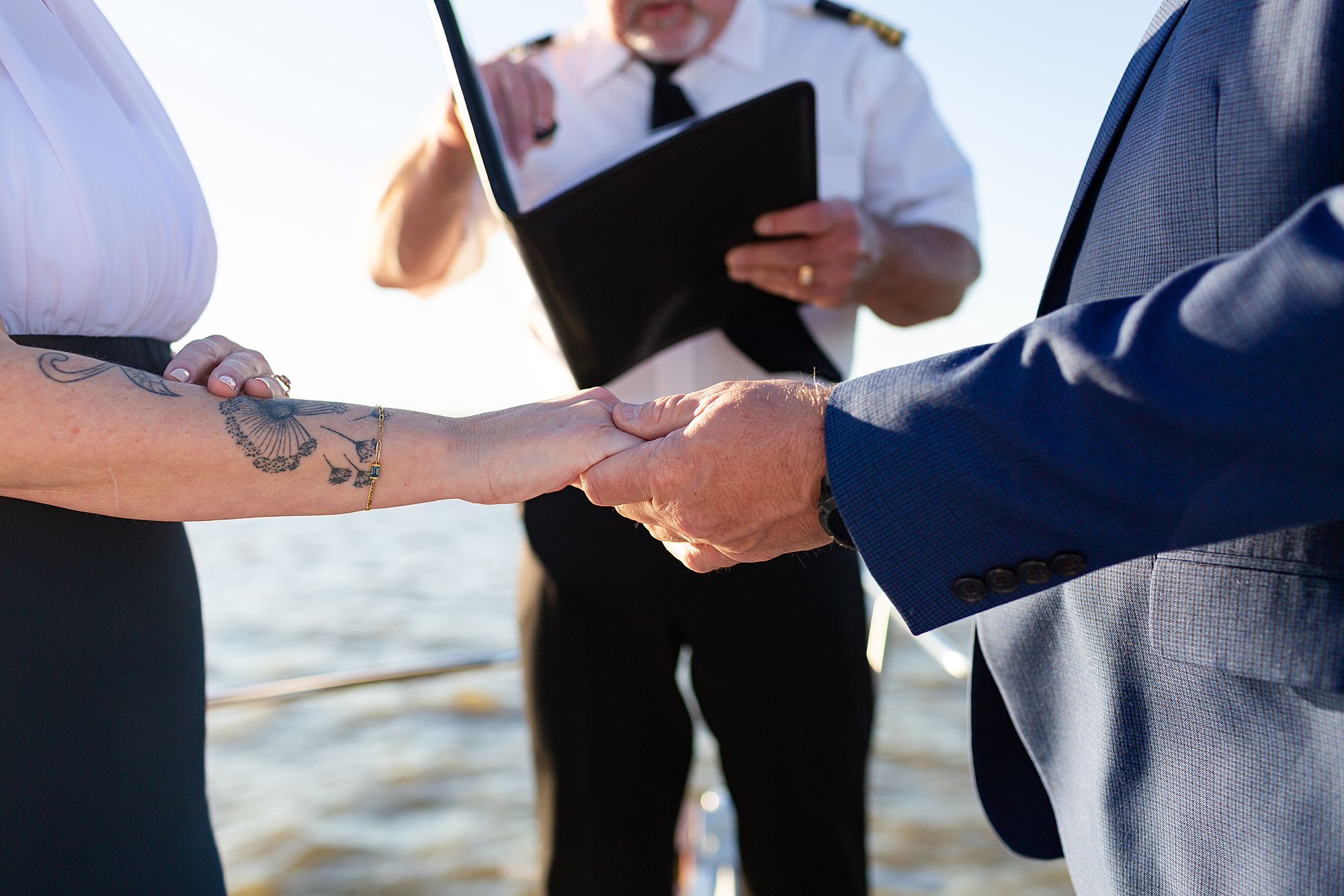 A closeup of a bride and groom holding hands during their elopement ceremony.