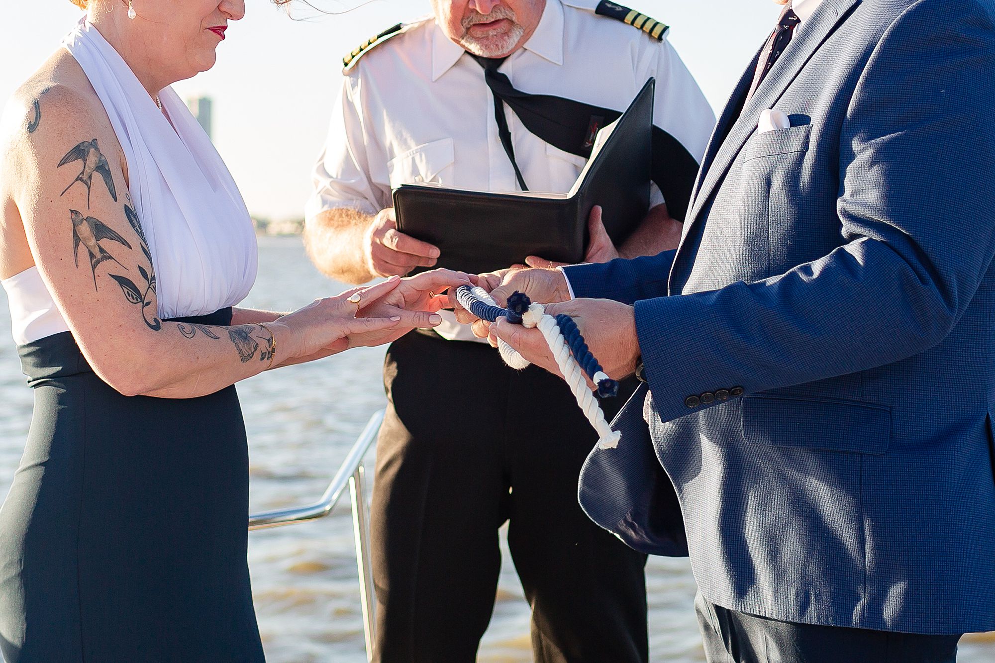 A closeup of a bride and groom holding a rope during their elopement ceremony.