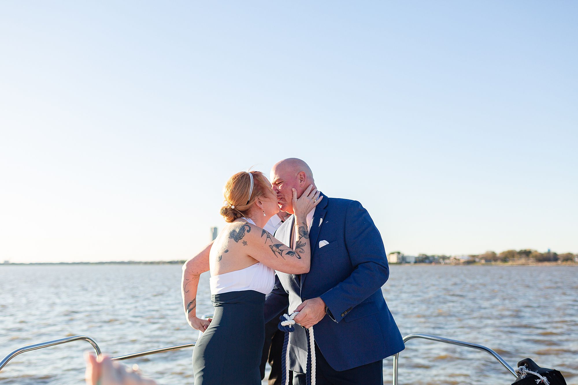 A bride and groom kiss at their elopement ceremony with a lake in the background.