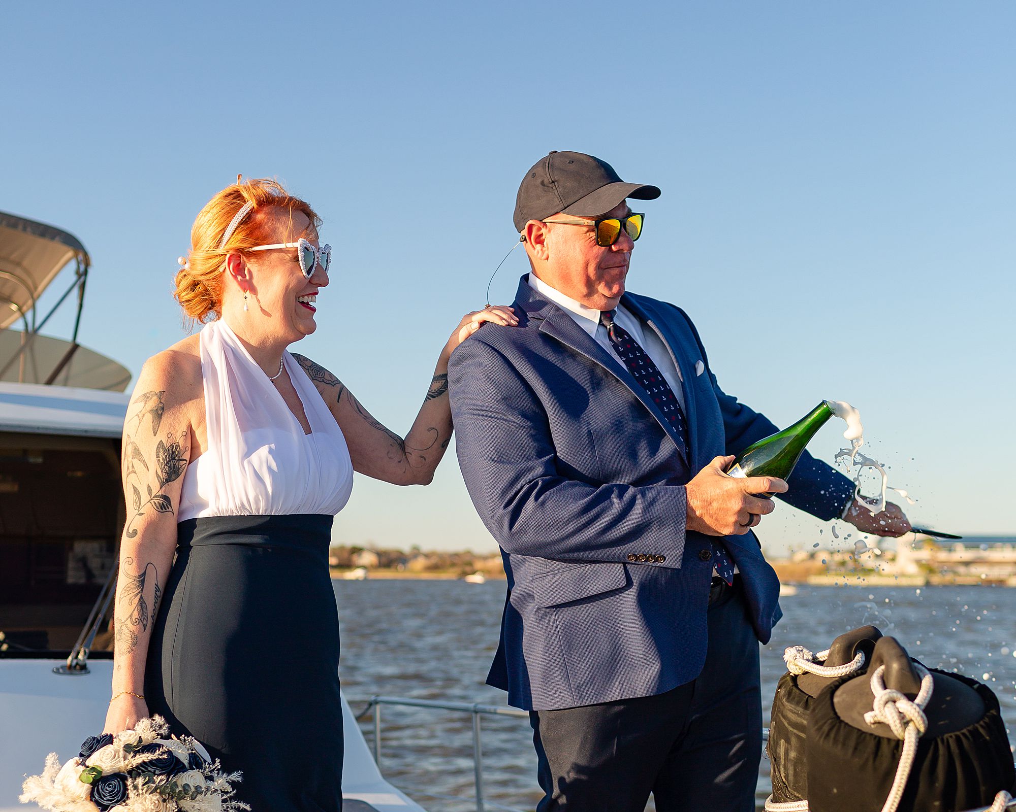 A bride laughs while her groom pops a bottle of champagne open at their Kemah yacht elopement.