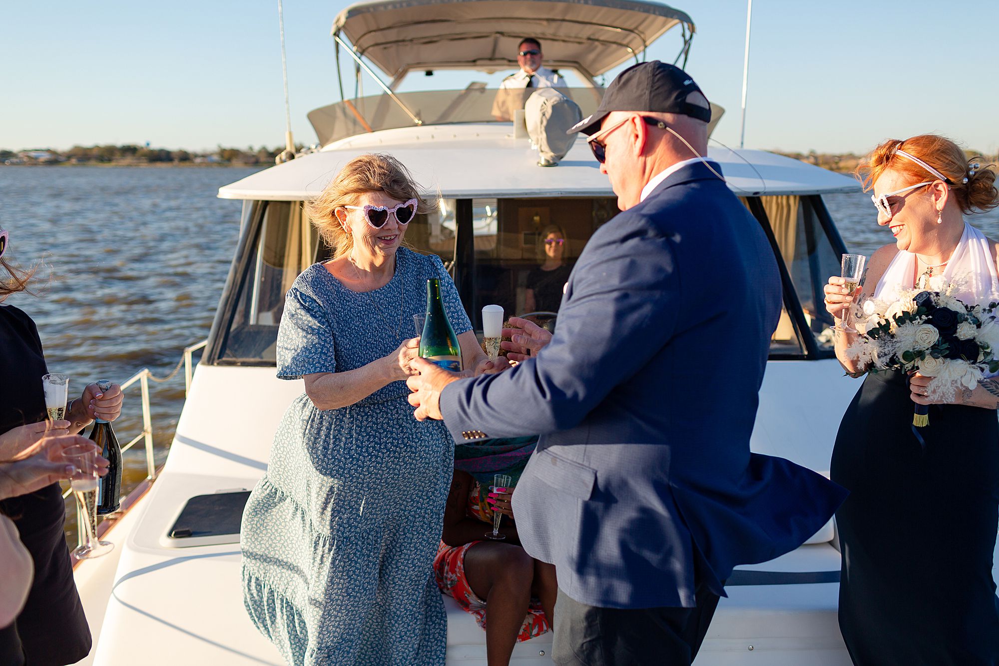 A groom passes out champagne to elopement guests on a yacht.