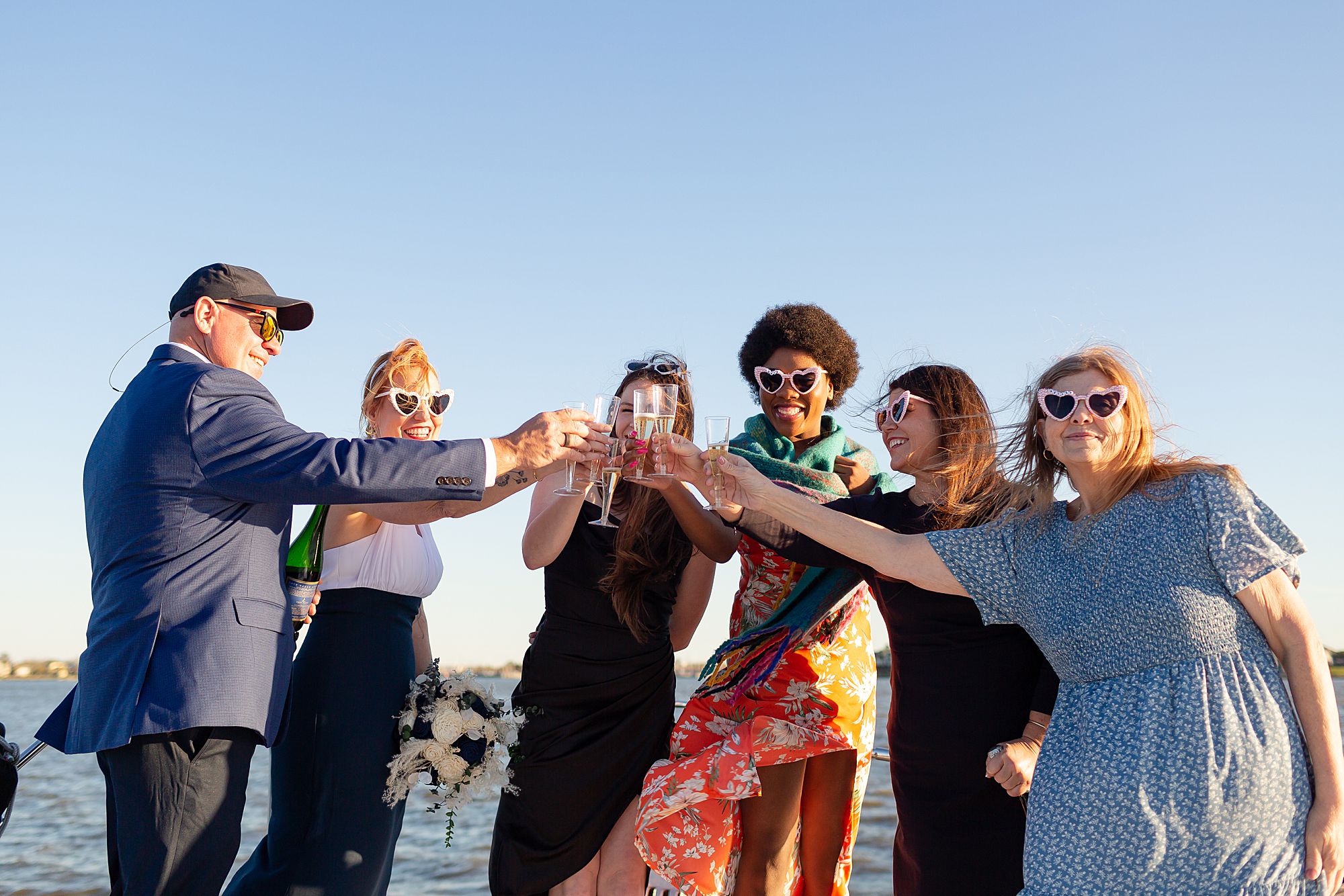 A bride and groom toast champagne with their elopement guests onboard a yacht in Kemah, Texas.