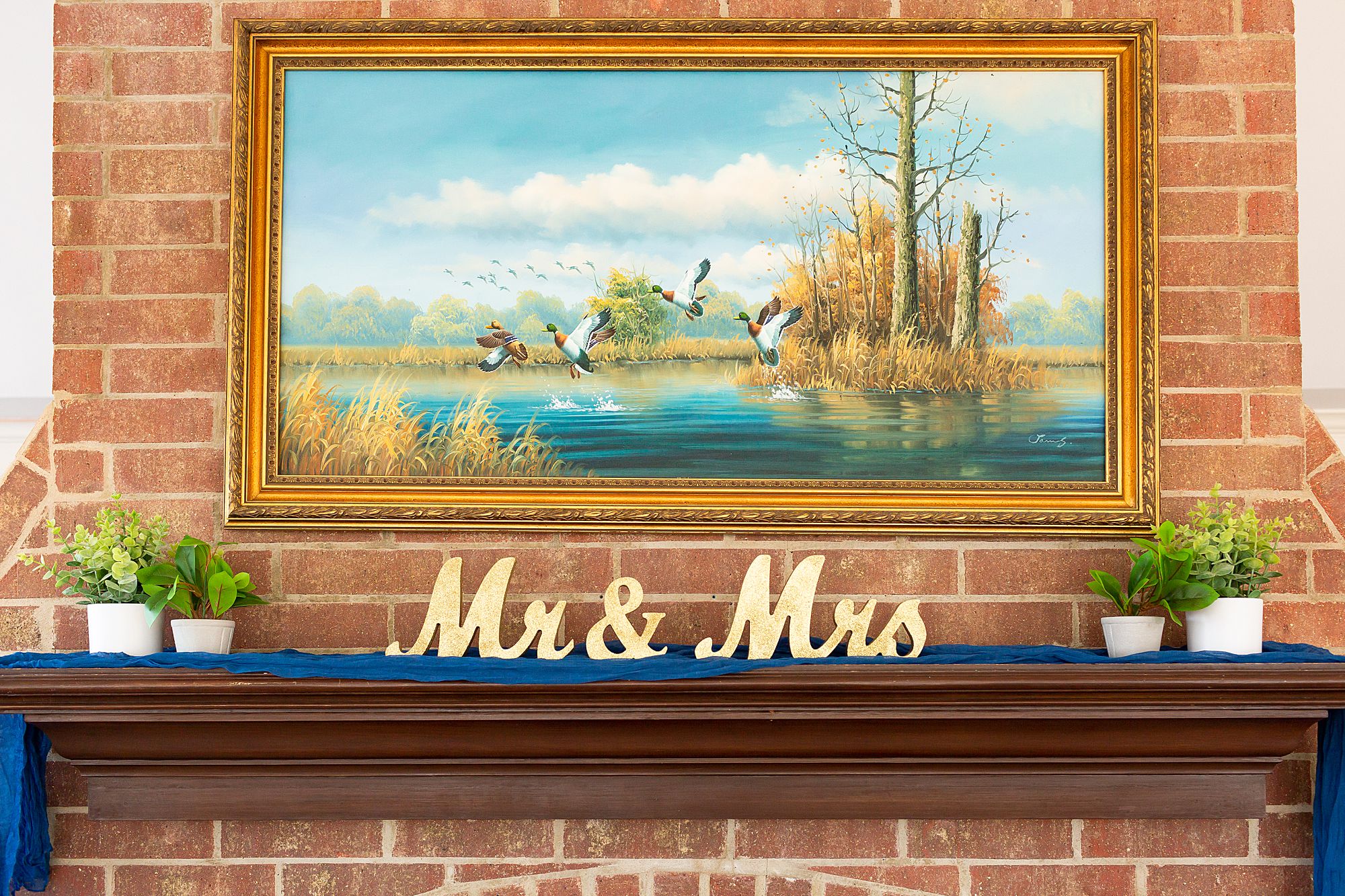 A mantel at Sundance Grill II decorated with a navy blue runner and Mr. and Mrs. signs.