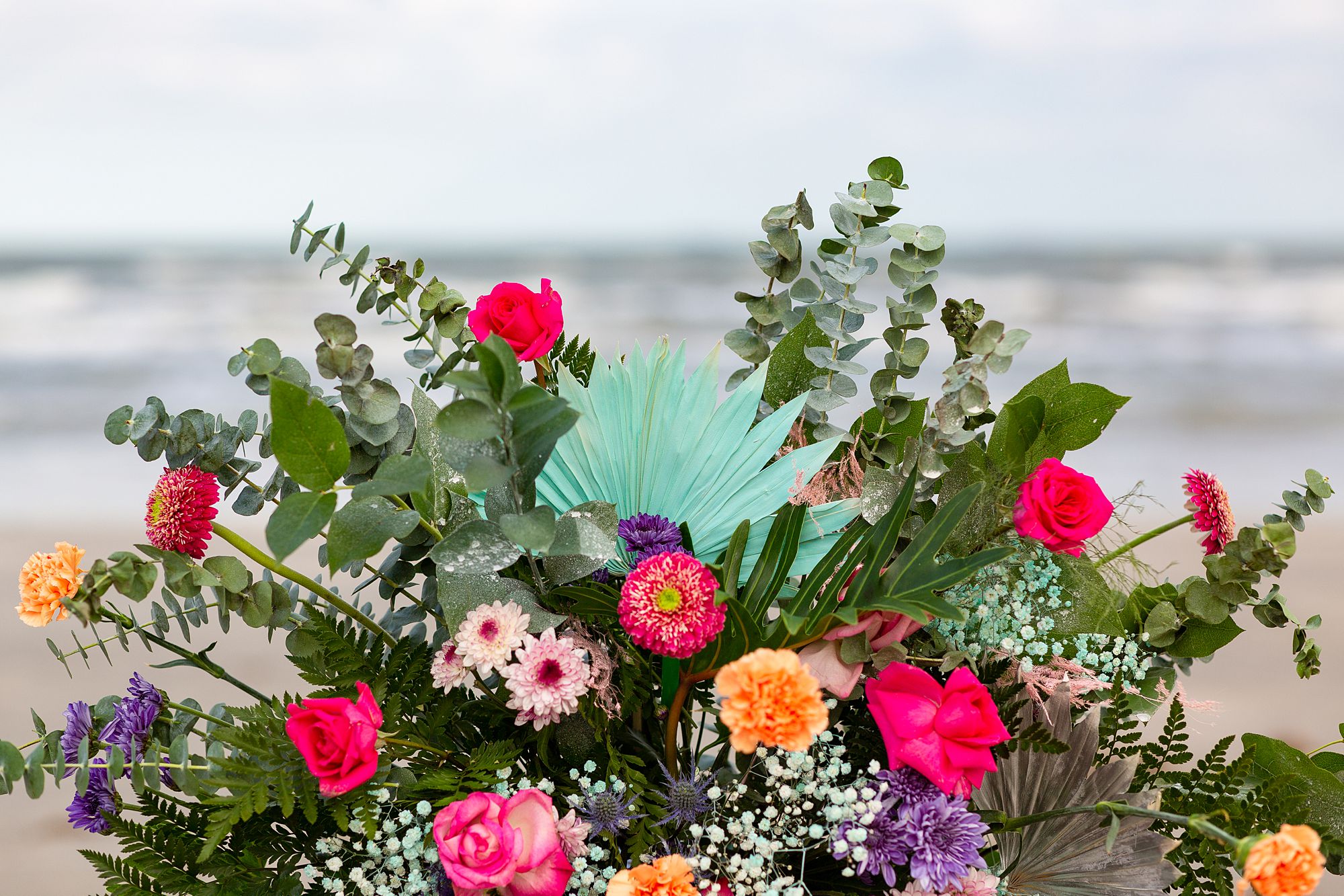Close up view of a hot pink, purple, and turquoise ceremony floral arrangement.